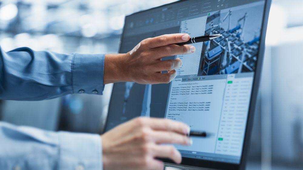 Close Up On Screen Of Desktop Computer With Automation Software For Autonomous Assembly Line At Modern Factory With Robotic Arms.