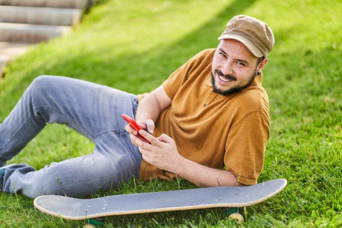 Relaxed man lying on the grass using the phone