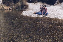 Positive woman and man resting on stone shore near river