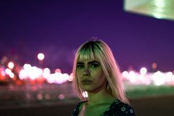 woman looking at camera against vibrant sky at dusk