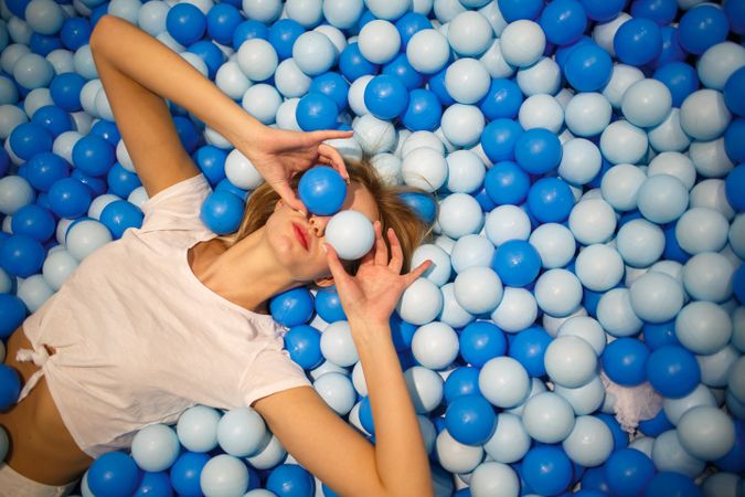 Woman in light t-shirt lying on blue and light balls