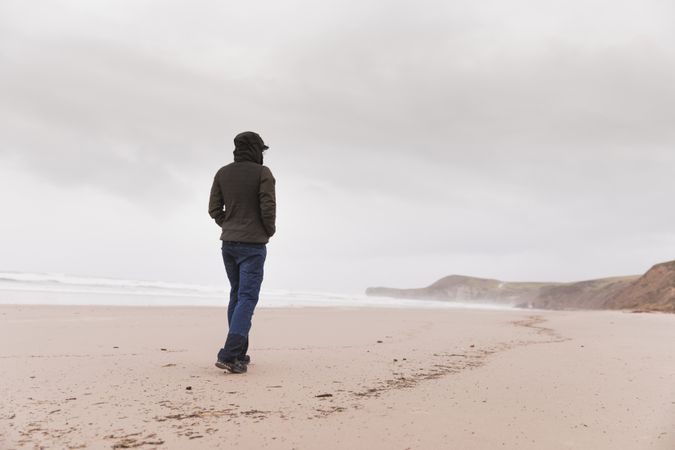 Man walking on sand shore near water