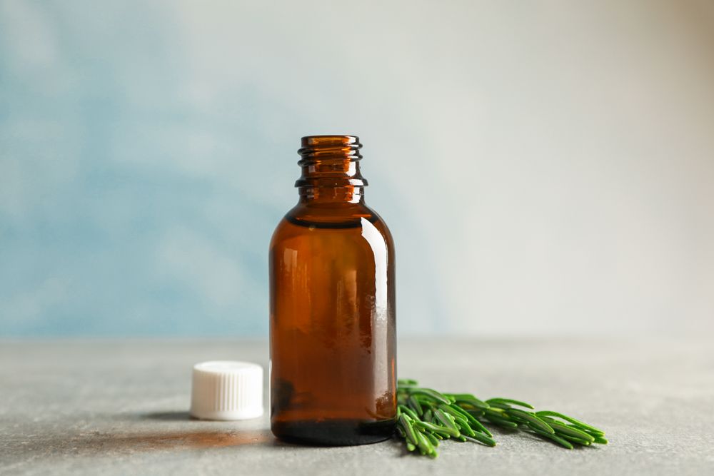 Rosemary oil and leaves on grey table, space for text