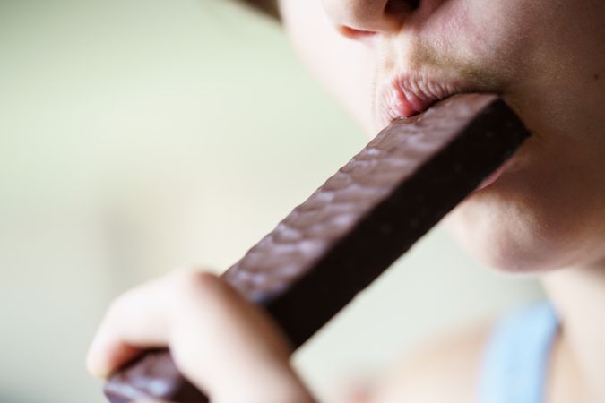 Teenage girl biting into protein bar