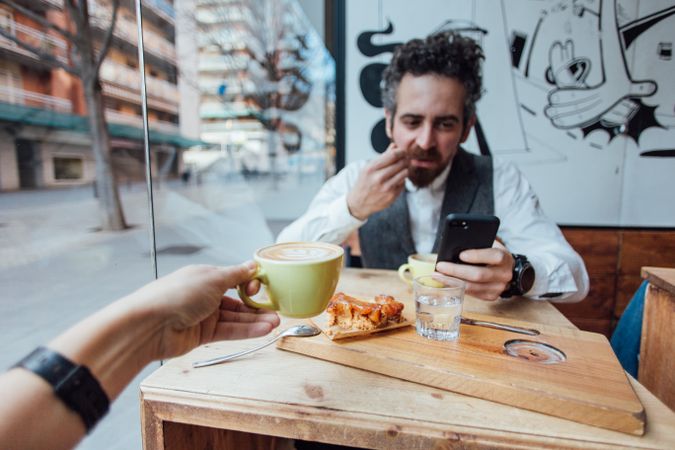 Two people with cappuccinos and eating dessert in hip cafe