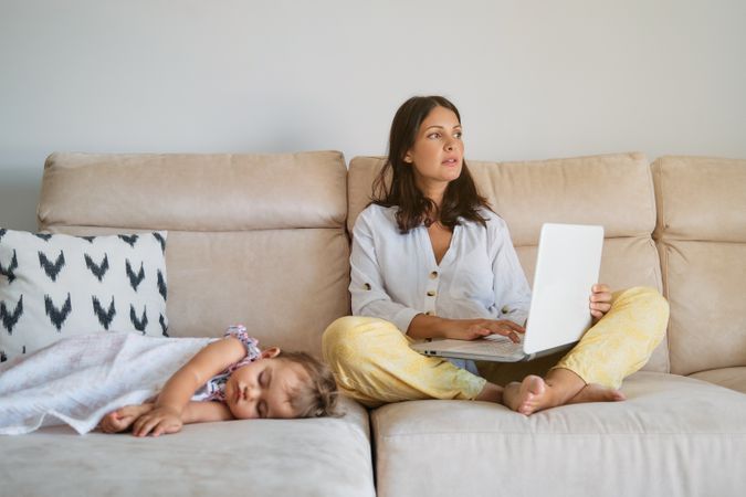 Mother working near sleeping daughter at home
