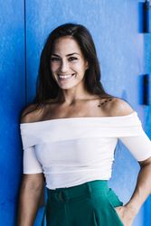 Portrait confident smiling young woman against a blue wall
