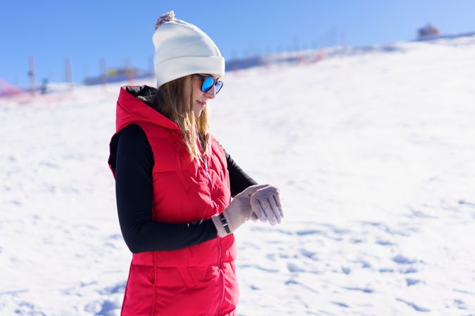 Woman in red snowsuit checking time on snowy mountain