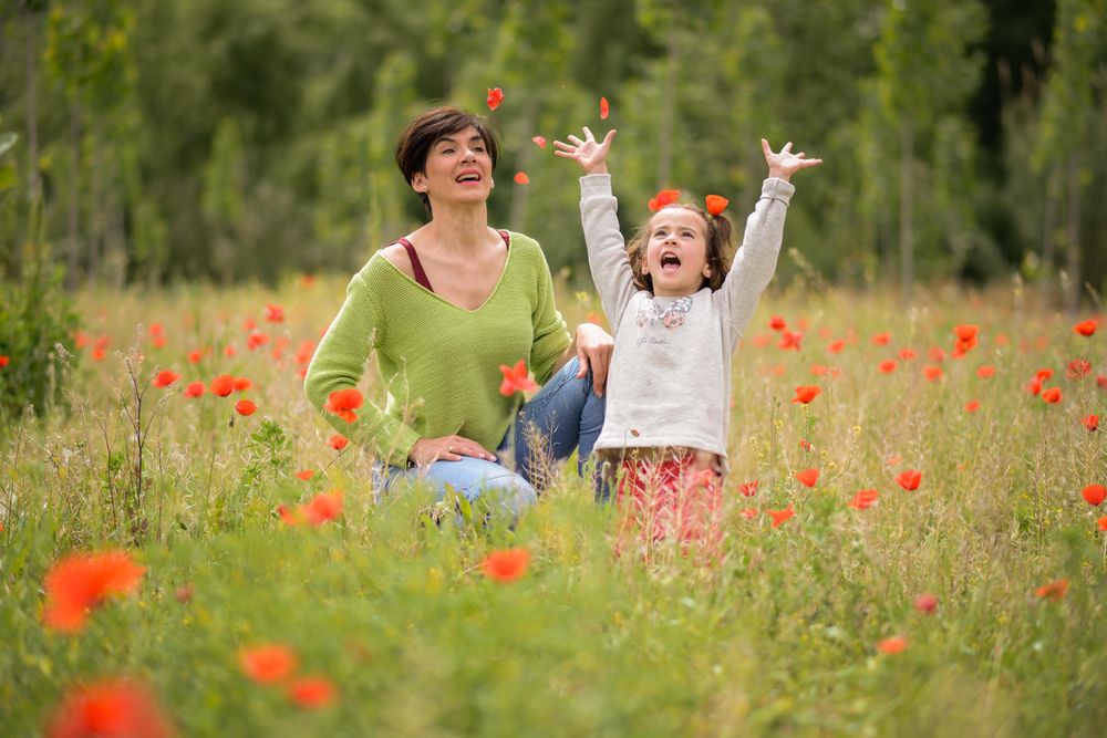 Happy mother with girl throwing poppies in the air