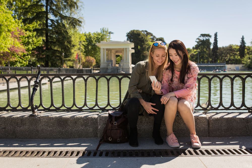 Multiethnic friends using smartphone on embankment