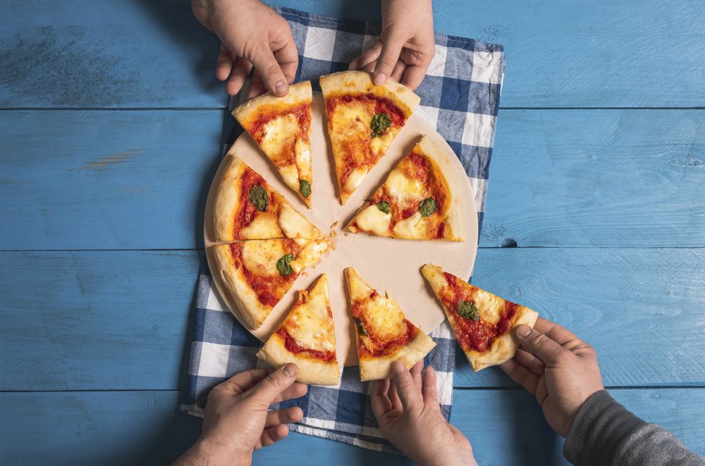 Friends grabbing pizza slices