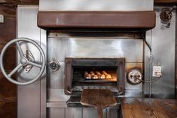 Some cupcakes are being baked inside of a big stone traditional oven