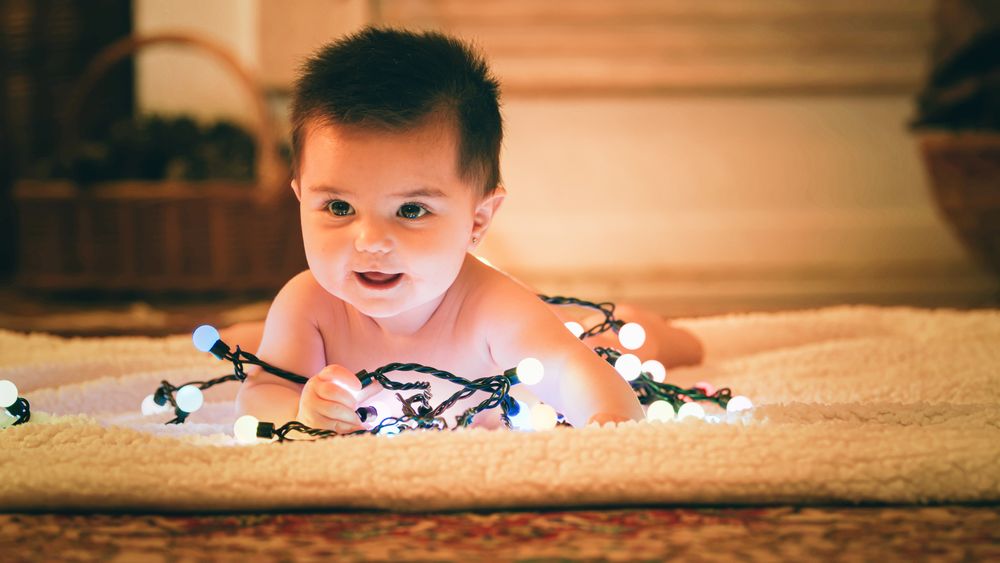 Baby playing with light garland on Christmas Day