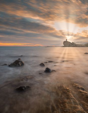 Sundown sky over sea and stony coast