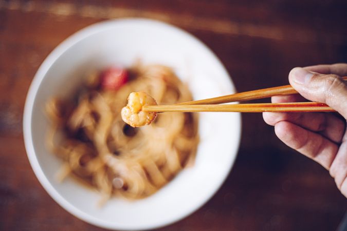 Faceless person eating dinner with chopsticks
