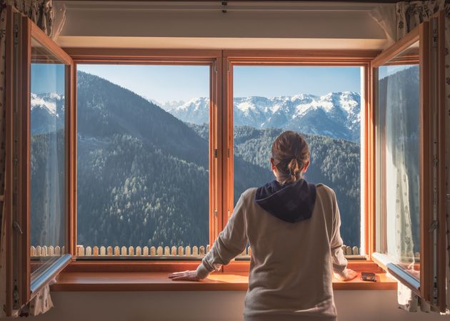 Anonymous woman looking at mountains from window