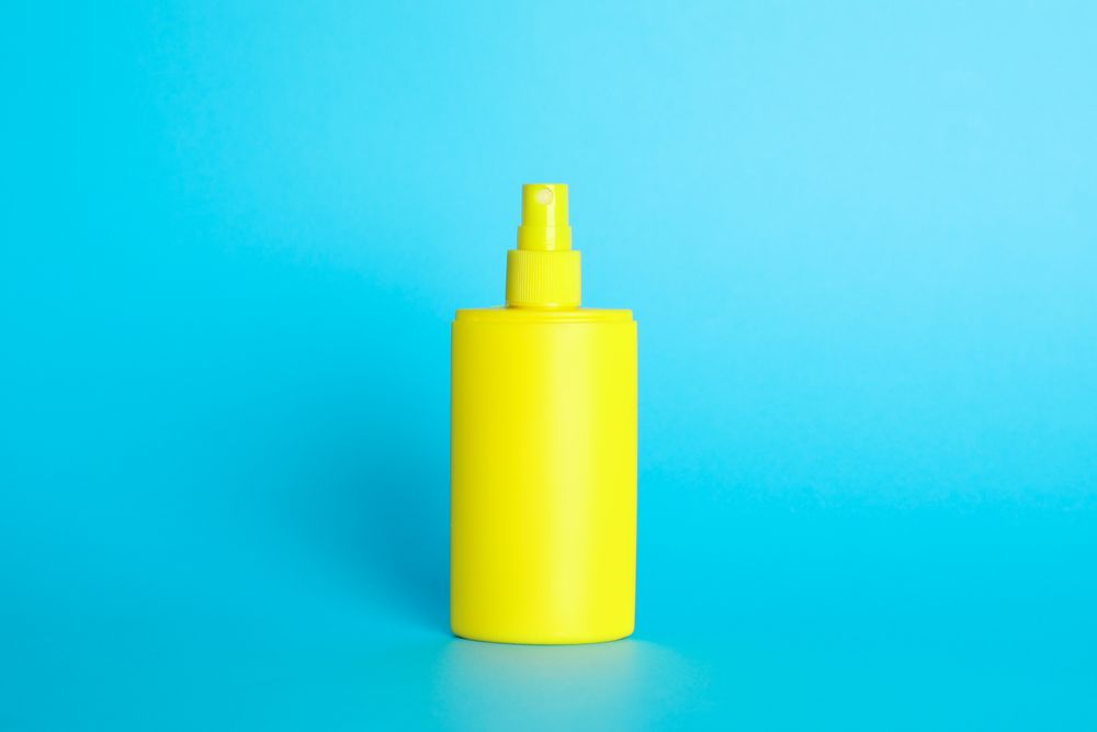 Sunscreen spray on color background, space for text