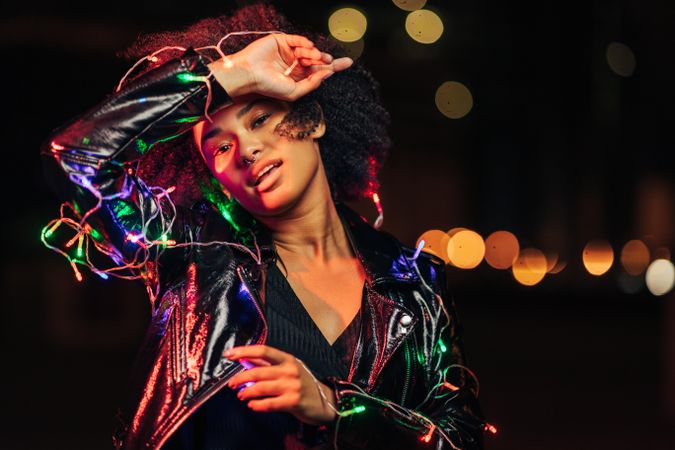 Black woman at night posing with holiday lights