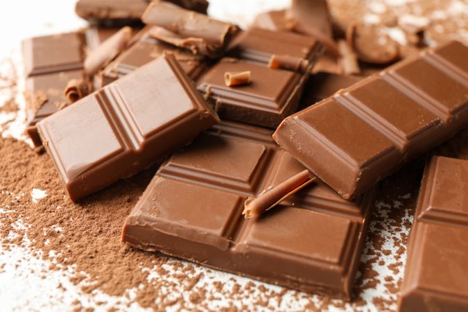 Tasty chocolate and powder on plain background. Sweet food