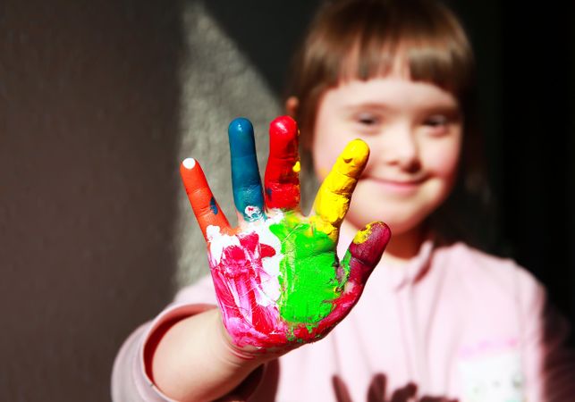 Focus on childs painted hand and girl smiling in the background