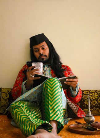 Indian man with long hair sitting and writing on a notebook