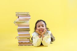 Female Little Kids Posing Beside Stacked Books