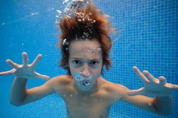 Frightening boy swimming in blue pool