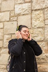 Satisfied young woman smiling while listening to music in earphones