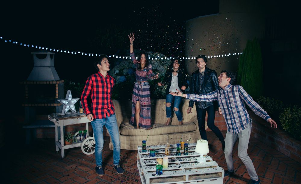 Happy friends playing around with confetti at party