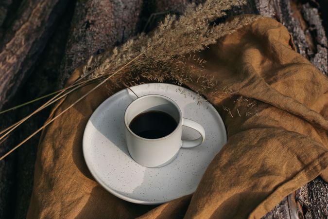 Cup of coffee on linen napkin in golden sunlight