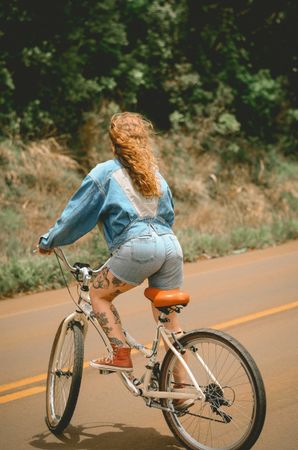Back view of woman riding on bicycle on road