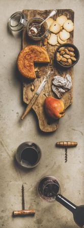 Cheese plate with glasses of red wine being poured, vertical composition