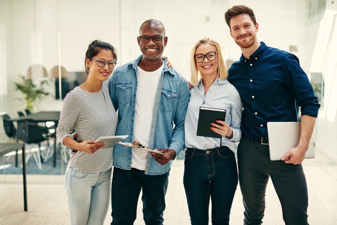 Multi-ethnic group of colleagues standing in line with their arms around each other