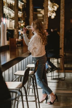 Stylish woman drinking wine in bar