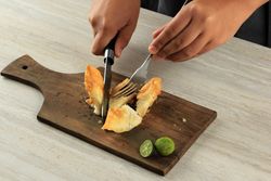 Person cutting deep fried wonton on board
