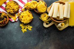Top view of variety of bowls of dry Italian pasta with space for text