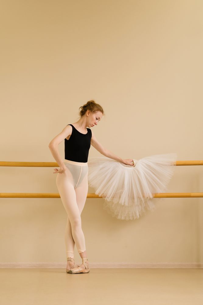 Ballet dancer resting hand on tutu while gazing thoughtfully