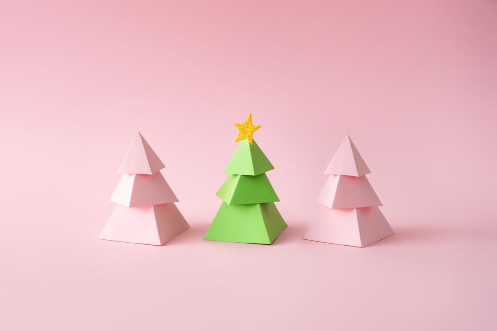 Pink and green paper Christmas trees on pink background