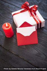 Candle, envelope and present on wooden table, vertical 5kno60