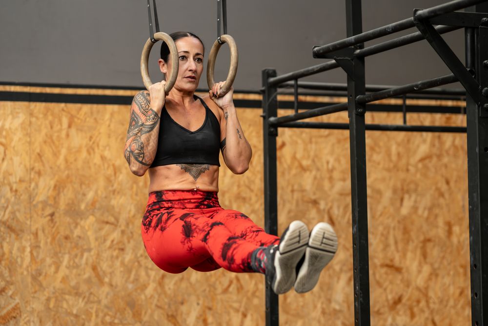 Woman performing core exercises hanging from olympic rings
