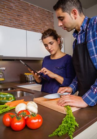 Couple checking digital tablet while cutting carrots