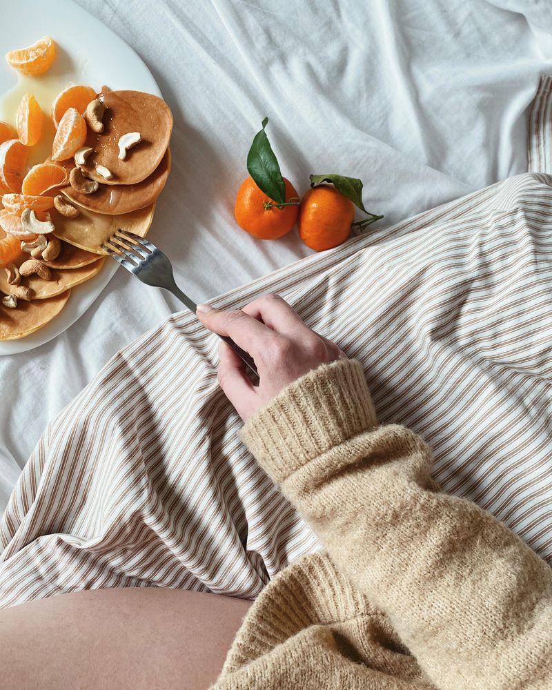 Hand reaching for mini pancakes on a duvet with magazine