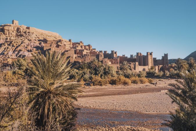 Ancient stone buildings near palms and water