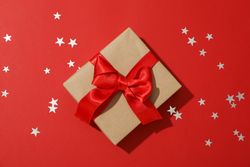 Gift box with bow on red background, space for text