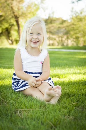 Cute Little Girl Sitting and Laughing in the Grass