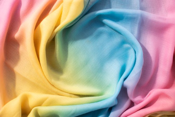 Gradient yellow blue pink and green fabric wavy spiral crumpled background texture with copy space.
