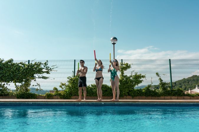 Friends playing with water pistols in the pool