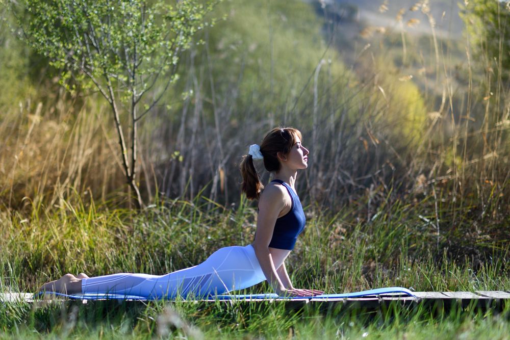 Female wearing sport clothes doing cobra yoga pose outside