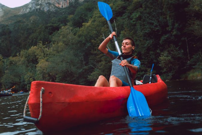 Young female kayaking on nature background