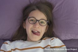 Girl wearing eyeglasses lying on bed 5X8r75